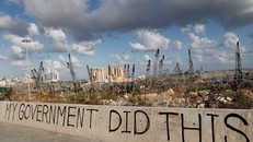 Dòng chữ tố cáo chính phủ Lebanon được viết trên 1 bức tường tại cảng Beirut sau vụ nổ kinh hoàng ngày 4/8/2020. Đắng sau là khung cảnh hoang tàn mà vụ nổ gây ra. (Ảnh: AP)