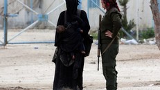 Một thành viên SDF đứng cạnh vợ một tay súng IS ở trại al Hol ở Syria. Ảnh: Reuters