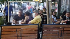 Thực khách ngồi ăn tại các bàn ngoài trời có vách nhựa ngăn cách. Ảnh: AP