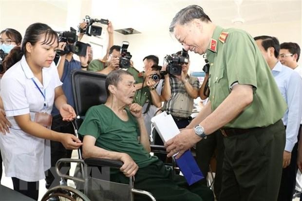 Đại tướng Tô Lâm thăm hỏi sức khỏe và trao quà tặng một đồng chí thương binh nặng đang điều dưỡng tại Trung tâm. (Ảnh: Đức Phương/TTXVN)