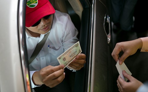 Một tài xế đưa tiền lẻ và được thối 100 đồng. Ảnh: Nguyễn Thành.