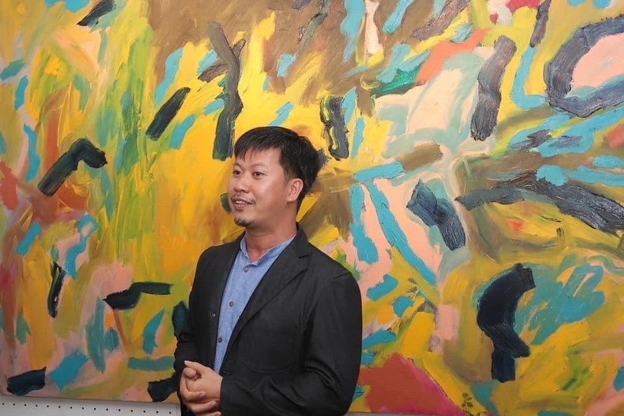 Họa sĩ Bùi Quang Viễn bên một tác phẩm của ông tại triển lãm.